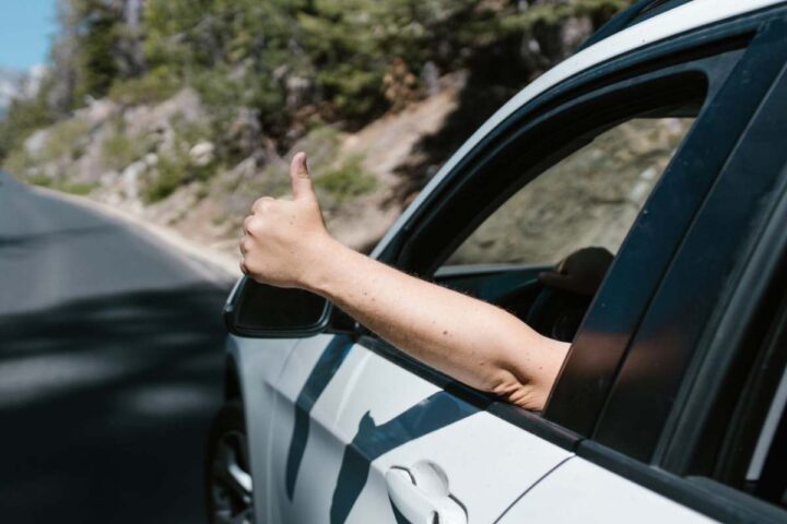 Un uomo mostra il pollice in su dal finestrino di un'auto