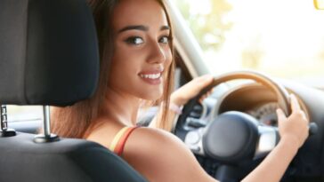 Una ragazza al volante di un'auto sorride