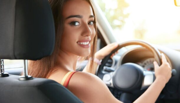 Una ragazza al volante di un'auto sorride