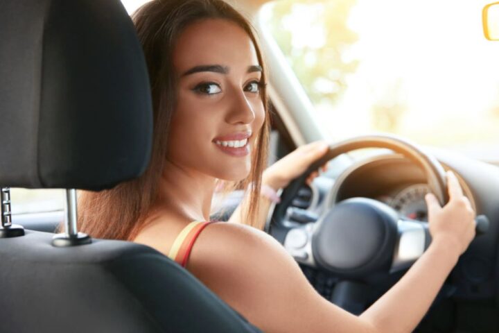 Una ragazza al volante di un'auto sorride