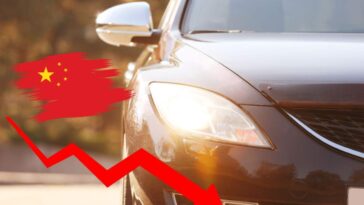 Un'auto con i fari accesi, una fraccia rossa che scende e la bandiera cinese