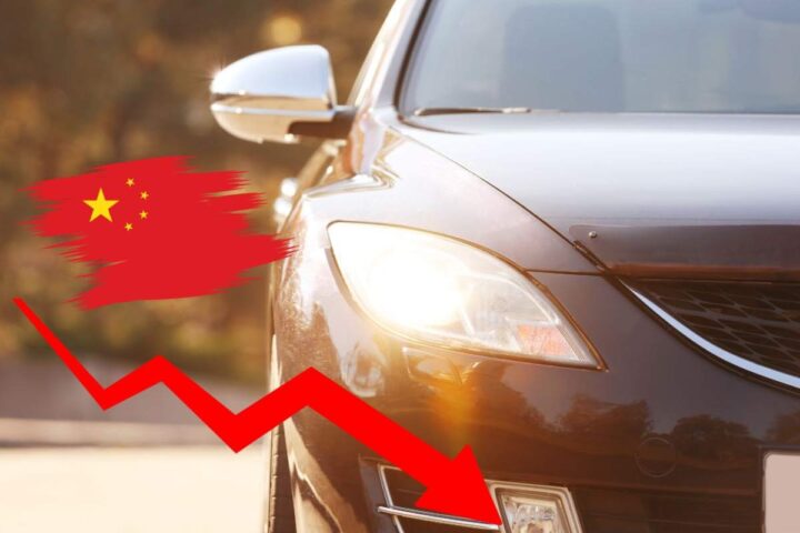 Un'auto con i fari accesi, una fraccia rossa che scende e la bandiera cinese