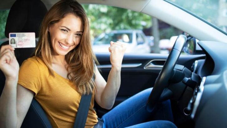 Una ragazza in auto mostra la patente appena conseguita 