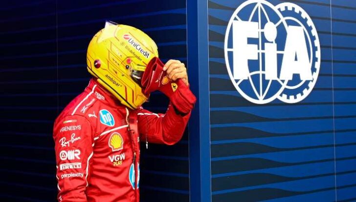 Lewis Hamilton con casco e tuta, dietro il logo FIA