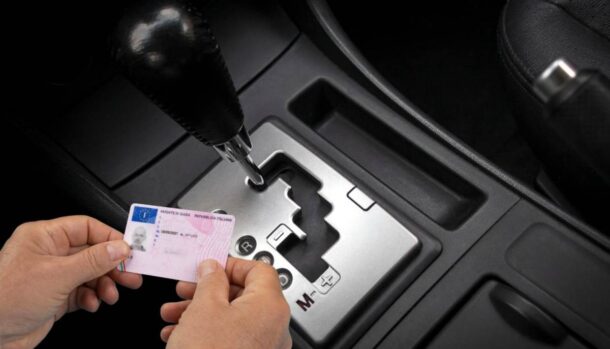 Un cambio automatico e due mani che tengono una patente