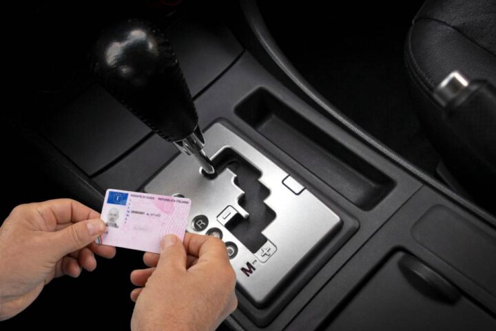 Un cambio automatico e due mani che tengono una patente