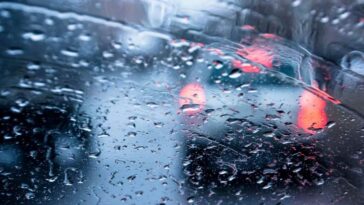 Il traffico visto da un parabrezza con gocce di pioggia