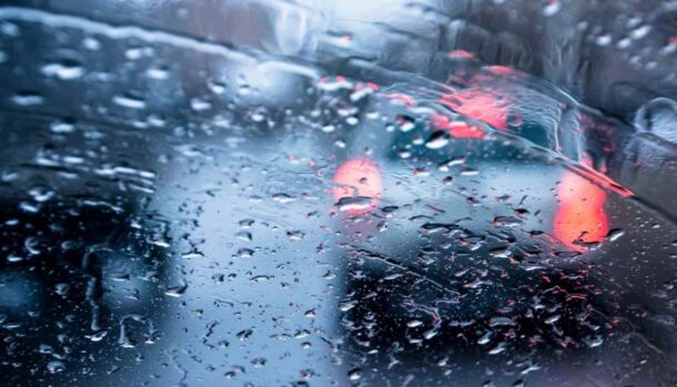 Il traffico visto da un parabrezza con gocce di pioggia