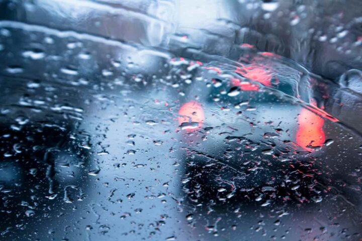 Il traffico visto da un parabrezza con gocce di pioggia