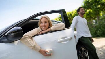 Una donna seduta in macchina con una tazzina di caffè in mano e un ragazzo in piedi