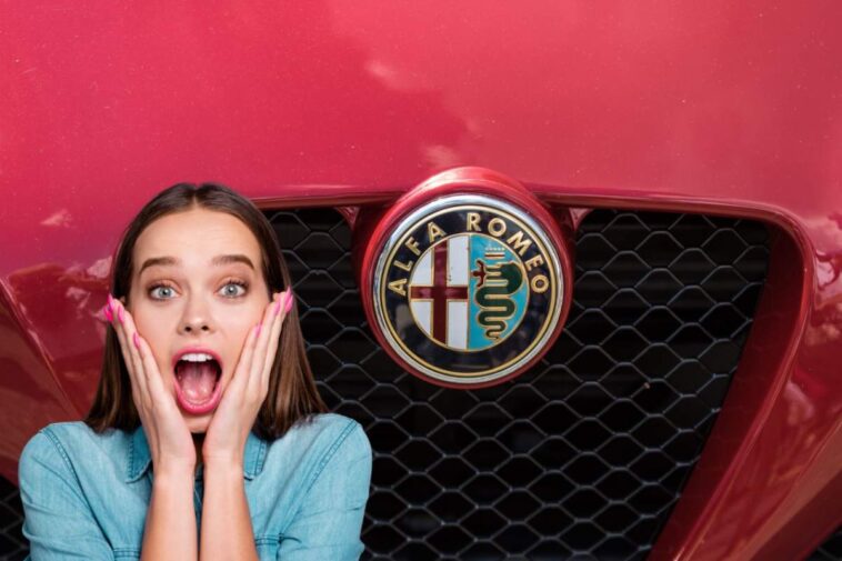Il frontale di un'auto rossa con logo Alfa Romeo e una ragazza a bocca aperta