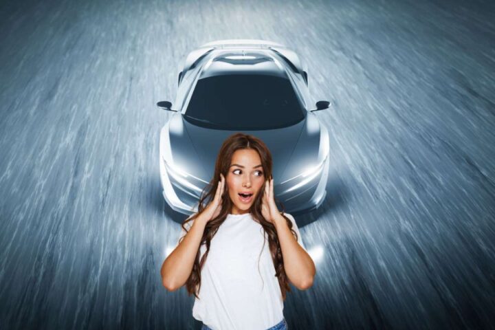 Un'auto sportiva e davanti una ragazza con espressione meravigliata