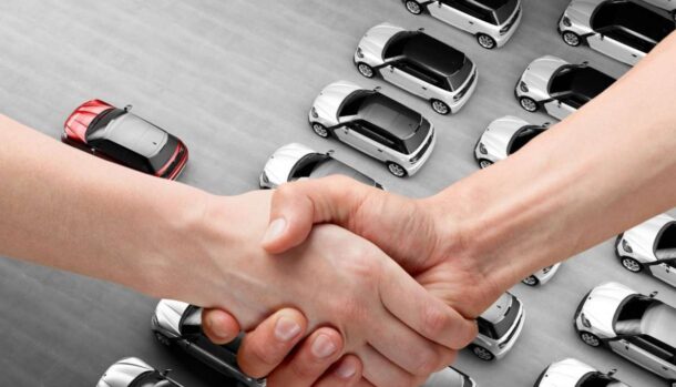 Delle auto viste dall'alto e due mani che si stringono