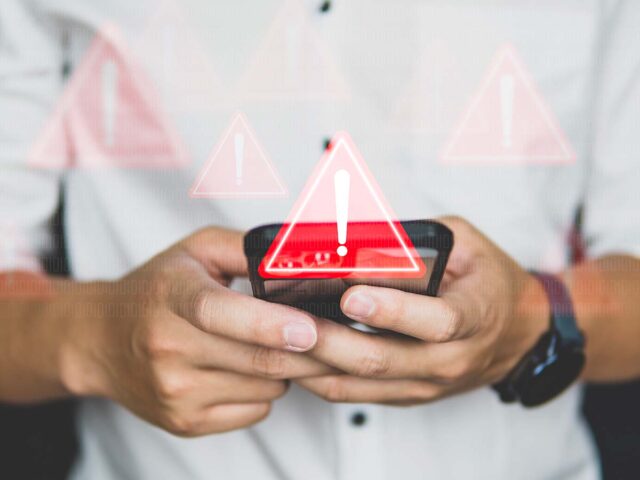 triangolo con punto esclamativo e dietro uno smartphone