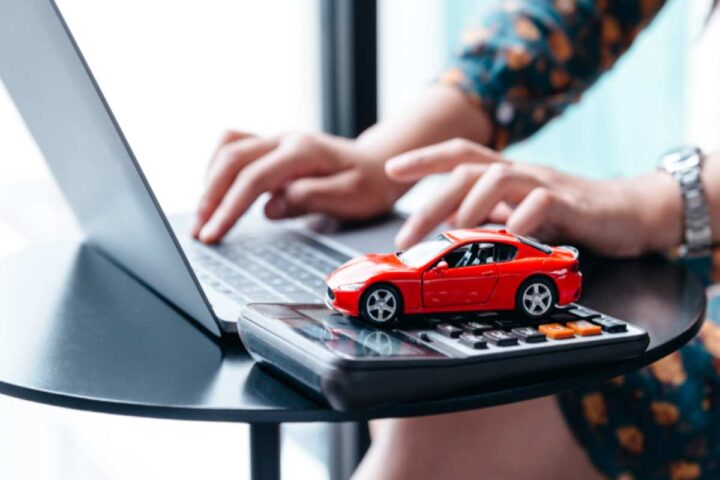 un computer con vicino una calcolatrice e un'auto in miniatura