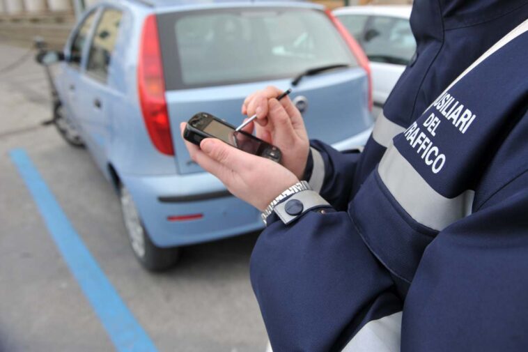 ausiliario traffico multa un'auto in sosta
